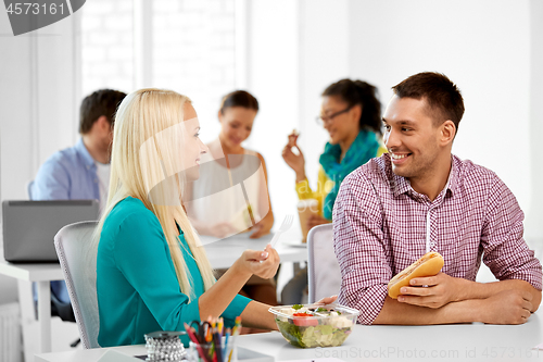 Image of happy colleagues having lunch and eating at office