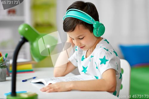 Image of boy in headphones with textbook learning at home