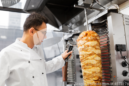 Image of chef slicing doner meat from spit at kebab shop