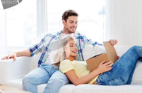 Image of happy couple opening parcel box at home