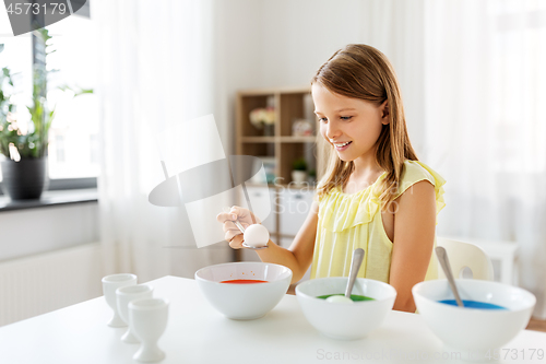 Image of girl coloring easter eggs by liquid dye at home