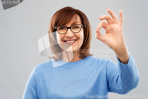 Image of happy senior woman in glasses showing ok hand sign