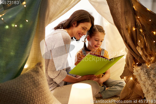 Image of happy family reading book in kids tent at home