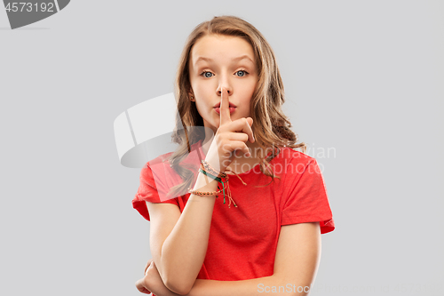 Image of teenage girl in red t-shirt with finger on lips