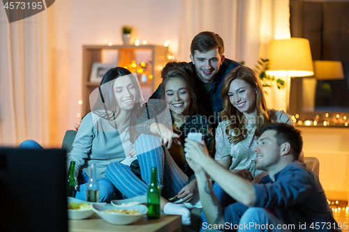 Image of friends with smartphone watching tv at home