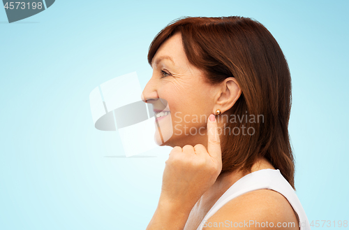 Image of smiling senior woman pointing to her earring