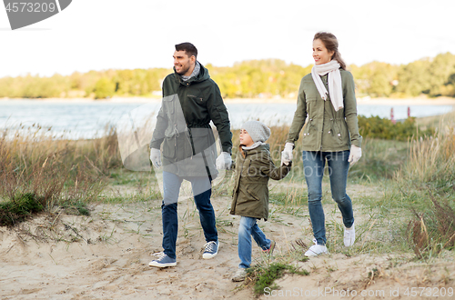 Image of happy family walking along autumn beach