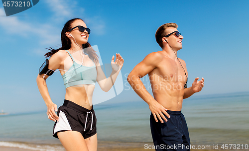 Image of couple with phones and arm bands running on beach