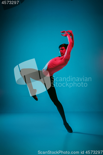 Image of The male athletic ballet dancer performing dance on blue background. Studio shot. Ballet concept. Fit young man. Caucasian model