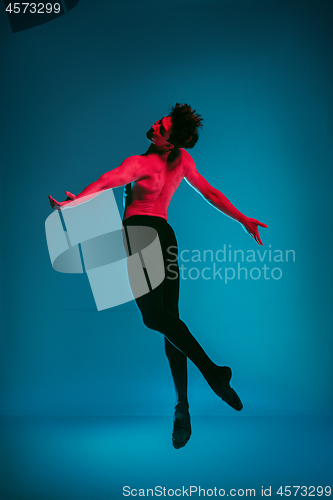 Image of The male athletic ballet dancer performing dance on blue background. Studio shot. Ballet concept. Fit young man. Caucasian model