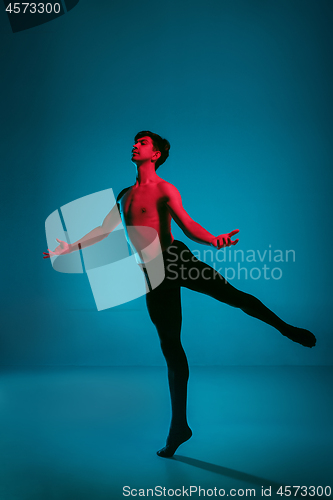 Image of The male athletic ballet dancer performing dance on blue background. Studio shot. Ballet concept. Fit young man. Caucasian model