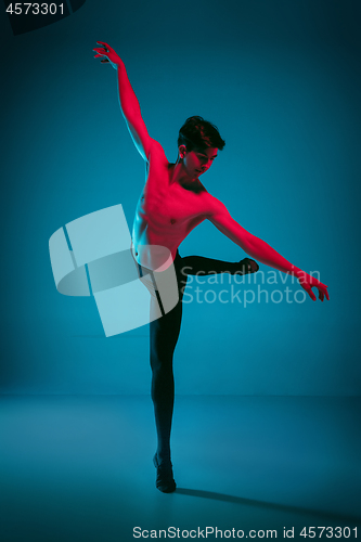 Image of The male athletic ballet dancer performing dance on blue background. Studio shot. Ballet concept. Fit young man. Caucasian model