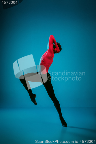 Image of The male athletic ballet dancer performing dance on blue background. Studio shot. Ballet concept. Fit young man. Caucasian model