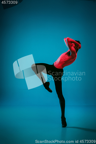 Image of The male athletic ballet dancer performing dance on blue background. Studio shot. Ballet concept. Fit young man. Caucasian model