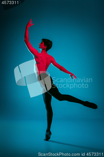 Image of The male athletic ballet dancer performing dance on blue background. Studio shot. Ballet concept. Fit young man. Caucasian model