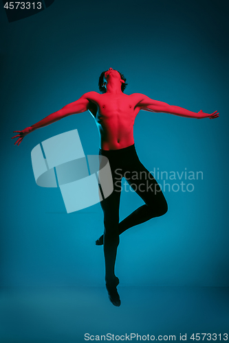 Image of The male athletic ballet dancer performing dance on blue background. Studio shot. Ballet concept. Fit young man. Caucasian model