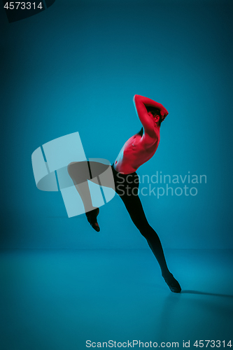 Image of The male athletic ballet dancer performing dance on blue background. Studio shot. Ballet concept. Fit young man. Caucasian model