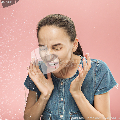 Image of Young woman sneezing, studio portrait