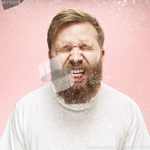 Image of Young handsome man with beard sneezing, studio portrait