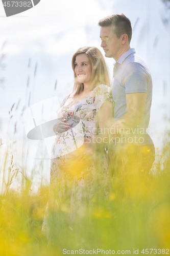 Image of Young happy pregnant couple hugging in nature.