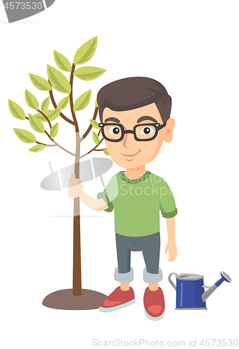 Image of Caucasian smiling boy in glasses planting a tree.