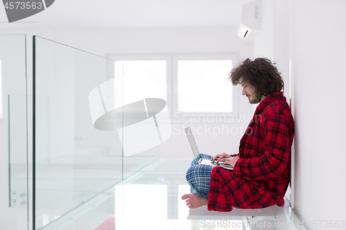 Image of young freelancer in bathrobe working from home