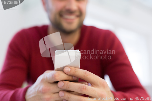 Image of young man using a mobile phone  at home