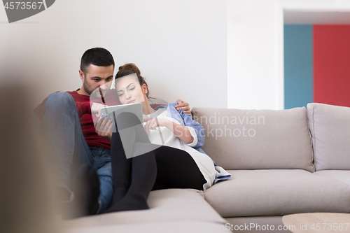 Image of couple relaxing at  home with tablet computers