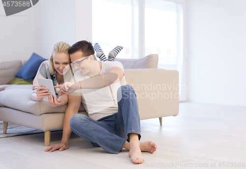 Image of couple relaxing at  home with tablet computers