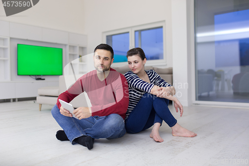 Image of Young Couple using digital tablet on the floor