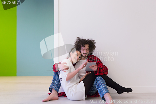 Image of Young Couple using digital tablet on the floor