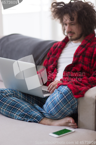 Image of man freelancer in bathrobe working from home