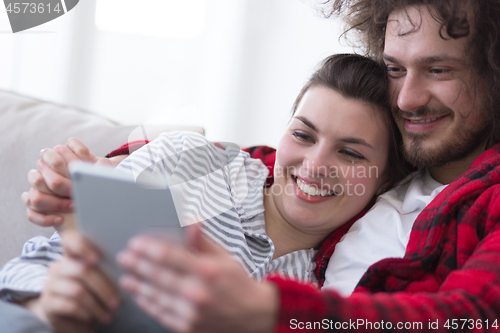 Image of couple relaxing at  home with tablet computers
