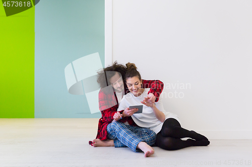 Image of Young Couple using digital tablet on the floor