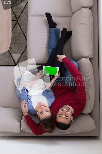 Image of couple relaxing at  home with tablet computers