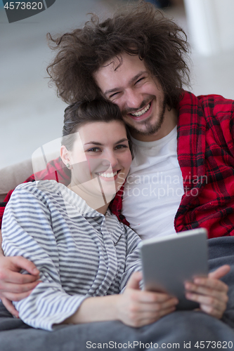 Image of couple relaxing at  home with tablet computers