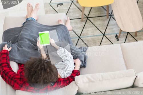 Image of couple relaxing at  home with tablet computers