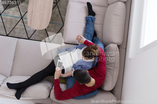 Image of couple relaxing at  home with tablet computers