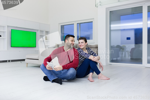 Image of Young Couple using digital tablet on the floor