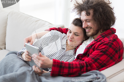 Image of couple relaxing at  home with tablet computers