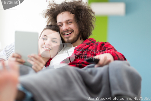 Image of couple relaxing at  home with tablet computers