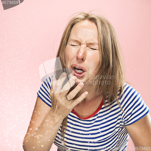 Image of Young woman sneezing, studio portrait