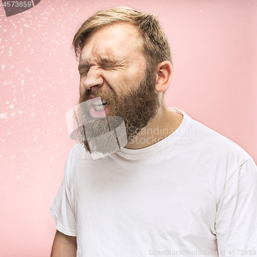 Image of Young handsome man with beard sneezing, studio portrait