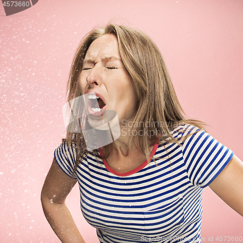 Image of Young woman sneezing, studio portrait