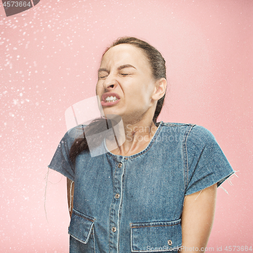 Image of Young woman sneezing, studio portrait