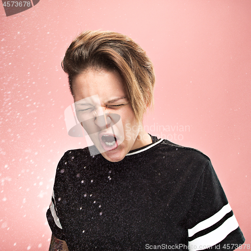 Image of Young woman sneezing, studio portrait