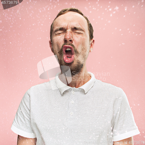 Image of Young handsome man with beard sneezing, studio portrait