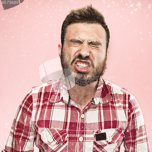 Image of Young handsome man with beard sneezing, studio portrait