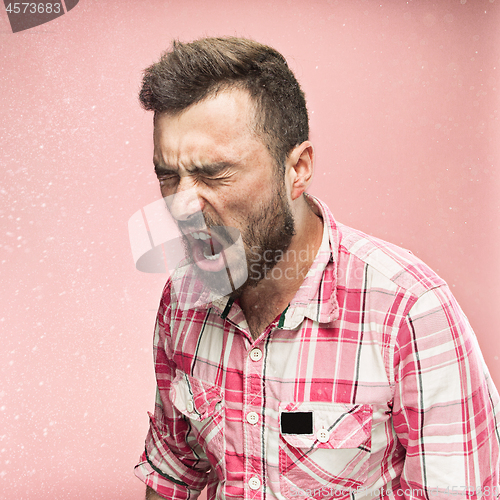 Image of Young handsome man with beard sneezing, studio portrait