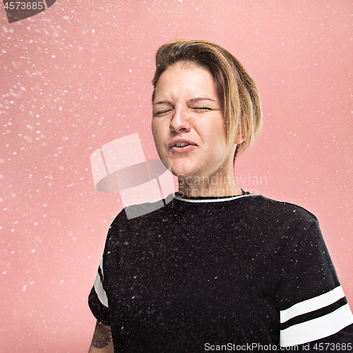 Image of Young woman sneezing, studio portrait